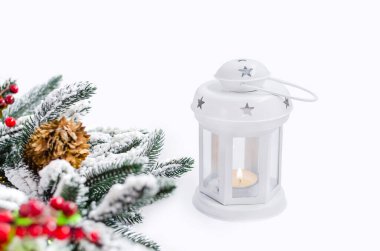 Noel şamdanı feneri yanan mum ve köknar dalı beyaz ahşap arka planda.