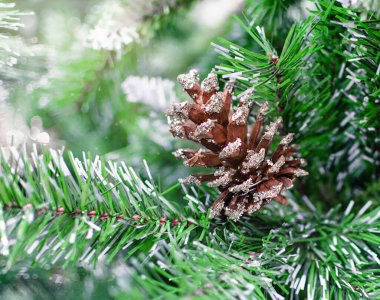 Yılbaşı arkaplanı, bir Noel ağacının yeşil yapay dallarının arka planında çam kozalağı.