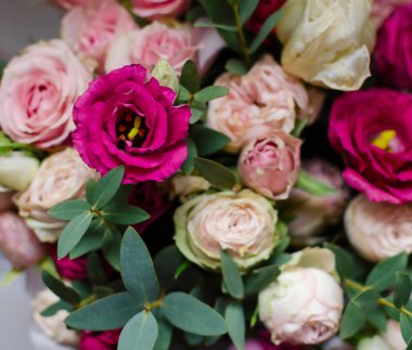 Renkli bir düzende, yemyeşil yapraklarla çevrili çeşitli pembe ve krema çiçekleri yer alır. Sahne taze ve doğal bir estetik yakalar, her türlü kutlama ve dekor için mükemmeldir..