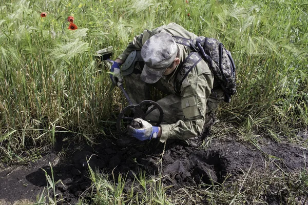 Homem sentado em camuflagem usando um detector de metais — Fotografia de Stock