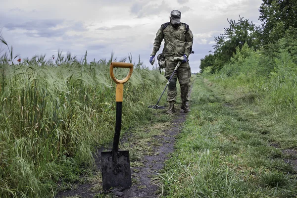 Man in camouflage using a metal detector — Stock Photo, Image