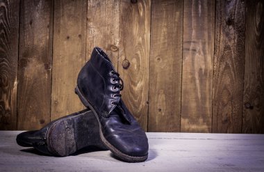 Siyah deri çizmeler stand ahşap zemin üzerinde