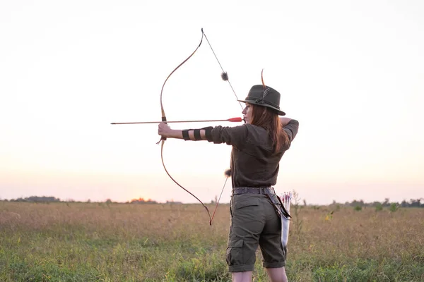 woman with bow outdoors in the field