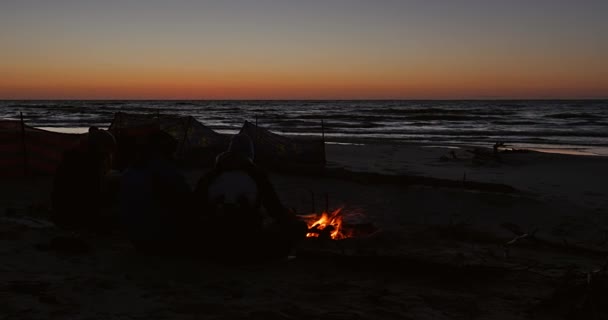Pessoas sentadas ao lado do fogo na praia — Vídeo de Stock
