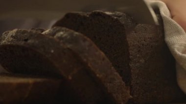 Kesme dilimleri, kahverengi ekmek ahşap kurullarında, ağır çekim. Karanlık ekmek close-Up. bıçak kesim 