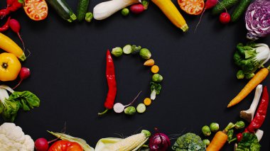 D. Havuç, kabak ve soğan harfleri siyah bir masanın üzerinde yer alır. sebzeden oluşan mektup.