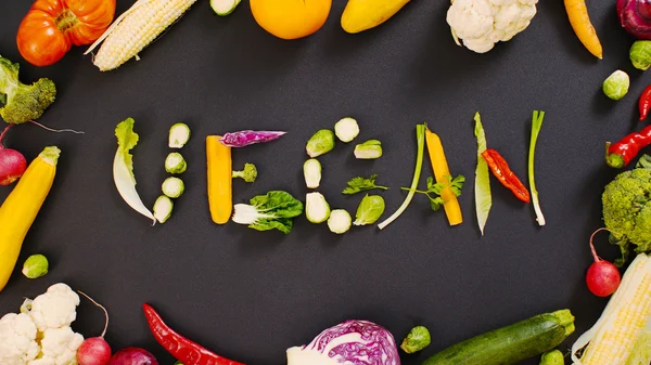 Sebzeler kelime vegan yaptı. Siyah arka plandaki sebzeler. Siyah arka planda kelime vegan. 