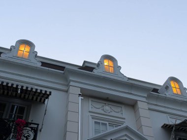 Dusk 'taki Beyaz Bina' da Dormer Windows 'tan Ilık Parıltı