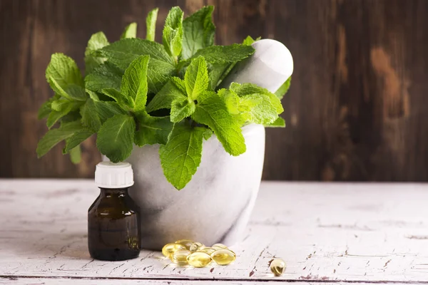 Ramas de menta, aceite de menta y pastillas sobre la mesa de madera — Foto de Stock