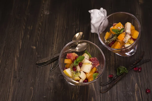 Fruit salad in glass bowls over dark background — Stock Photo, Image