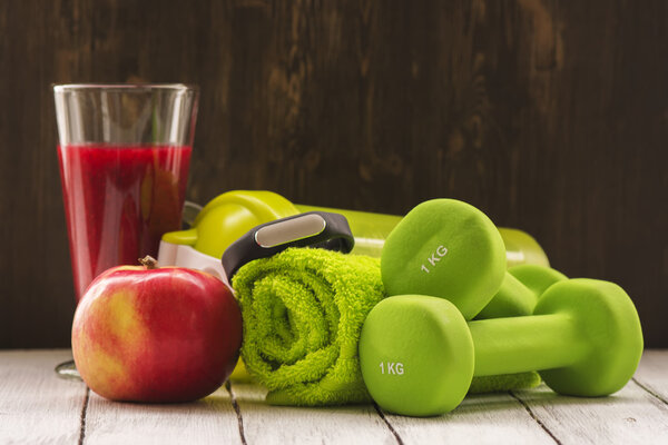 Fitness or diet concept: dumbbells, fresh red smoothie, apple