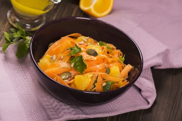 Salada com cenoura fresca, fatias de laranja, sementes de abóbora e girassol — Fotografia de Stock