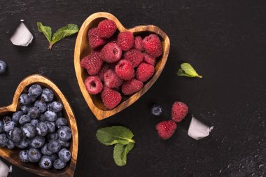 Yaban mersini ve kalp içinde ahududu ahşap kase şeklinde