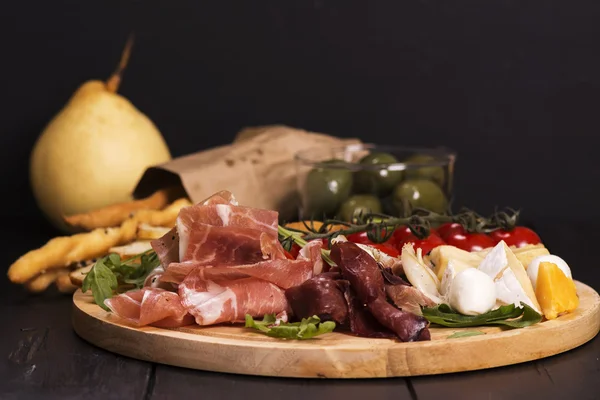 Various types of italian appetizers: ham, cheese, grissini, olives, fruits — Stock Photo, Image