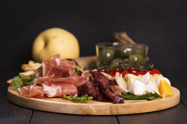 Various types of italian appetizers: ham, cheese, grissini, olives, fruits — Stock Photo, Image