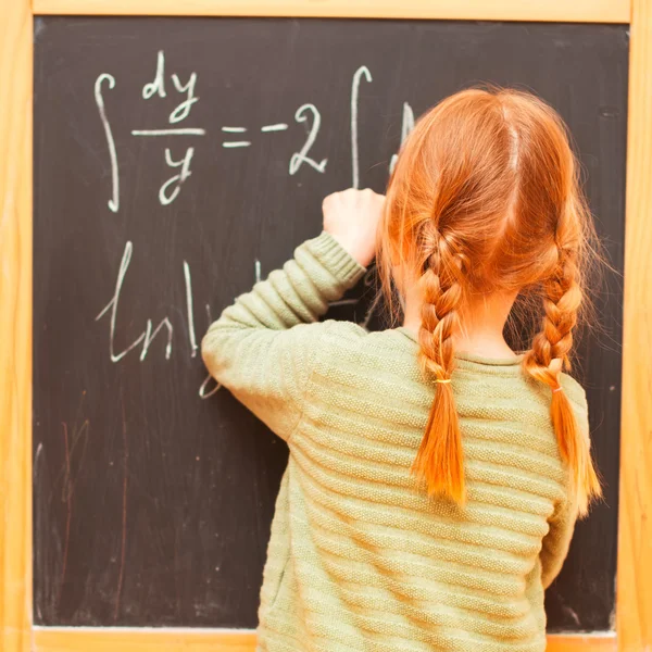 Little girl writes on the blackboard — Stock Photo, Image