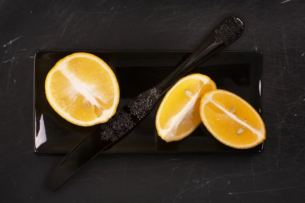 Κόβουμε τα λεμόνια σε μαύρο γδαρμένο πέτρινο φόντο — Φωτογραφία Αρχείου