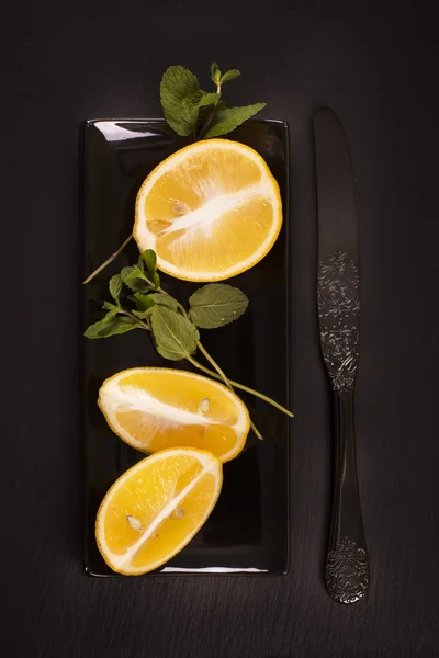 Limones cortados con menta sobre mesa de piedra negra rayada —  Fotos de Stock