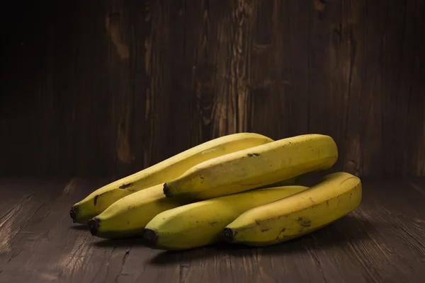 Bando de bananas maduras sobre fundo de madeira rústica — Fotografia de Stock