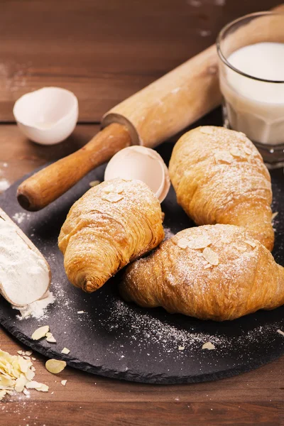 Fresh baked croissants with almond leaves — Stock Photo, Image