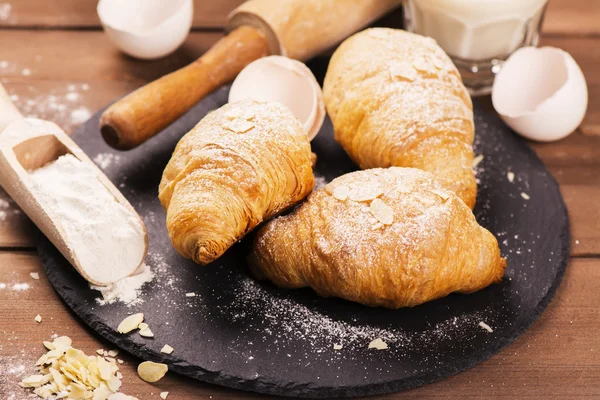 Fresh baked croissants with almond leaves — Stock Photo, Image