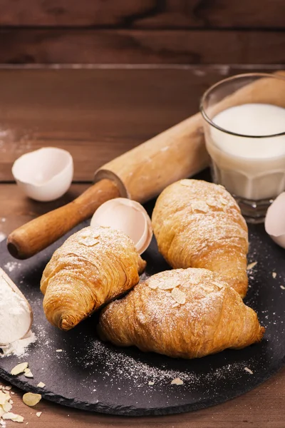 Fresh baked croissants with almond leaves — Stock Photo, Image