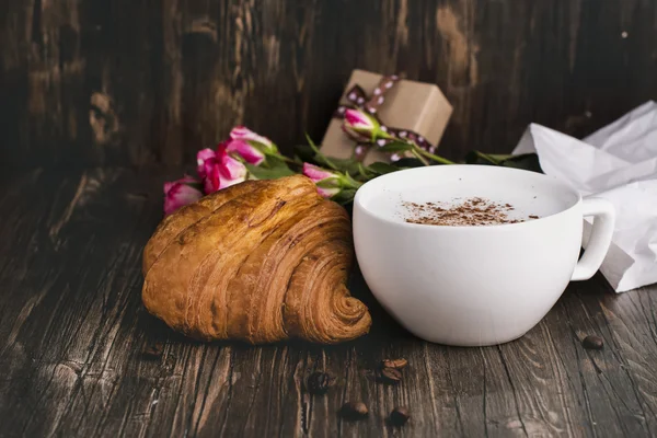 新鲜羊角面包和卡布奇诺咖啡在木桌 — 图库照片