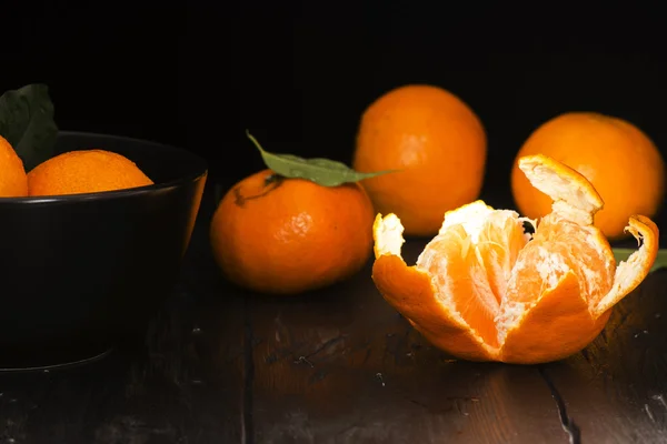 Mandarijnen met bladeren op oude donkere houten tafel — Stockfoto