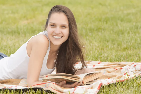 Усміхнена дівчина з книгою на відкритому повітрі — стокове фото