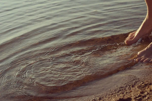 Füße machen Wellen im Wasser — Stockfoto