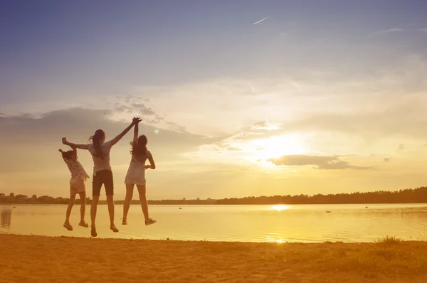 Familjen hoppa på solnedgången i sommar — Stockfoto