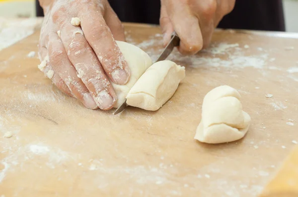 Руки кухаря нарізали тісто на дошці — стокове фото