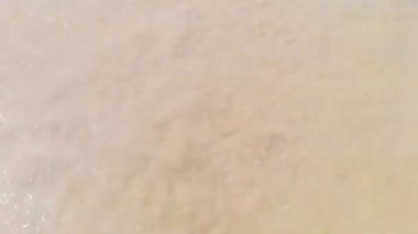 Yumuşak bir deniz dalgasının yakın çekimi köpükle yıkanan pürüzsüz altın kum. Sahilde huzurlu bir an, okyanusun ritmini ve doğanın basitliğini yakalıyor. Yüksek kaliteli FullHD görüntüler