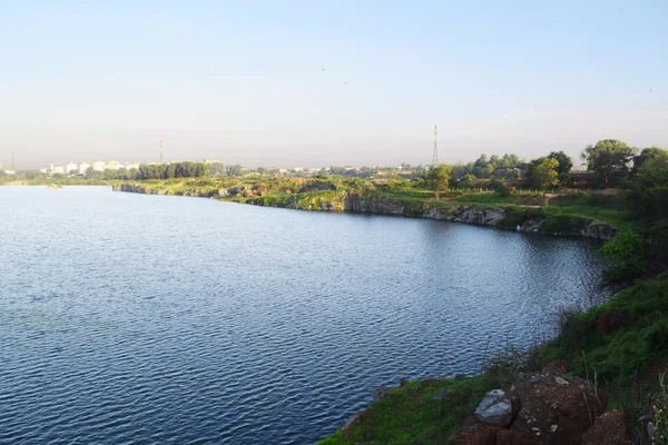 Rocky lake with some stones and grass in the bank — Stock Photo, Image