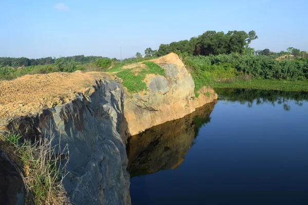 Lago roccioso con pietra e pianta riflettere sull'acqua — Foto Stock