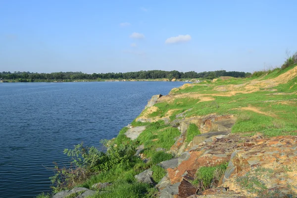Lago rochoso com algumas pedras e grama no banco — Fotografia de Stock