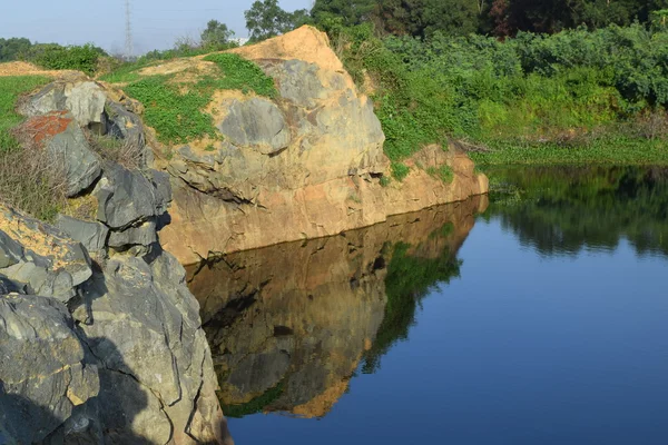 Rocky sjö med sten och anläggning reflektera över vattnet — Stockfoto