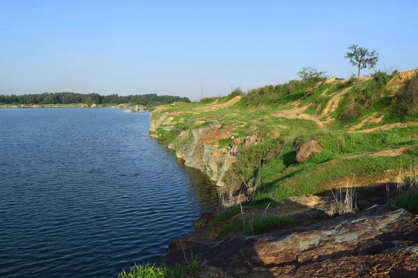 Lago roccioso con alcune pietre ed erba in banca — Foto Stock