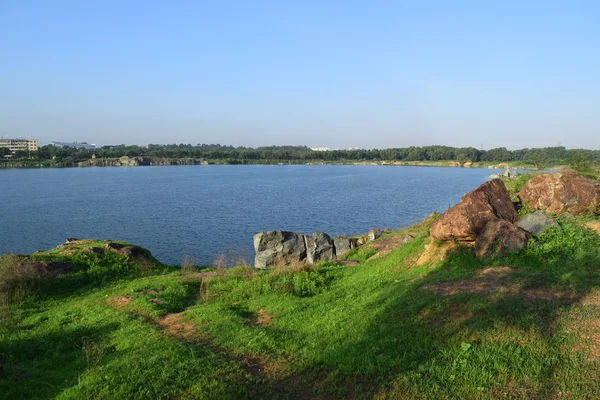 Lago rocoso con algunas piedras y hierba en la orilla —  Fotos de Stock