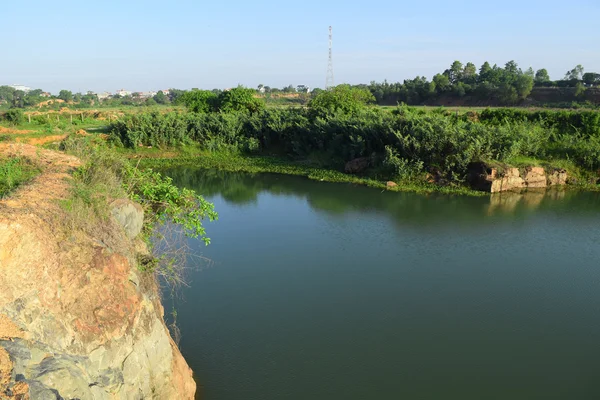 Rotsachtige lake met enkele stenen en gras in de bank — Stockfoto