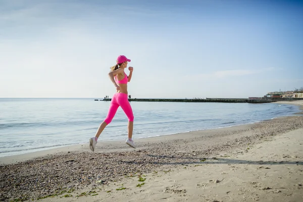 Jovem correndo e fazendo exercícios esportivos na costa do mar ao nascer do sol — Fotografia de Stock