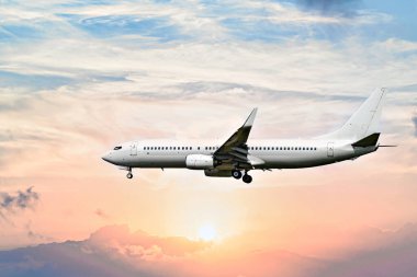 Yolcu uçağı beyaz bulutlu mavi gökyüzünün altında havaalanına iniyor.