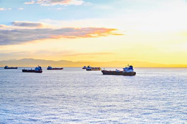 Kargo gemileri gün batımında Barselona limanına doğru yola çıkıyor.