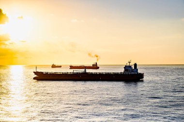 Kargo gemileri gün batımında Barselona limanına doğru yola çıkıyor.