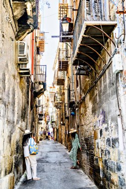 Palermo, Sicilya; 18 Temmuz 2025: Sicilya 'nın eski Palermo kentindeki dar ve tipik bir caddede iki turist geziniyor..