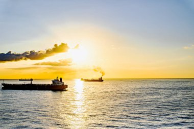 Kargo gemileri gün batımında Barselona limanına doğru yola çıkıyor.