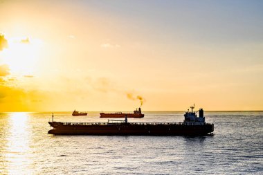 Kargo gemileri gün batımında Barselona limanına doğru yola çıkıyor.