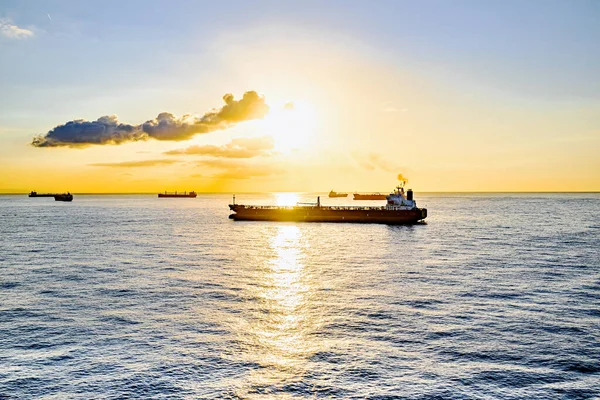Kargo gemileri gün batımında Barselona limanına doğru yola çıkıyor.