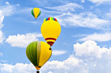 Mavi gökyüzünde beyaz bulutlarla uçan renkli sıcak hava balonu