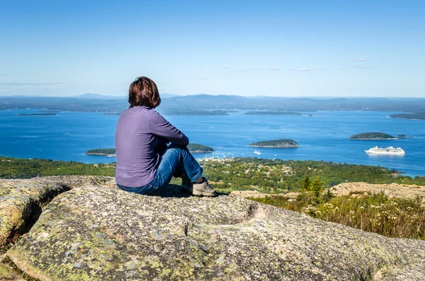 Женщина наслаждается Vista, сидя на скале — стоковое фото